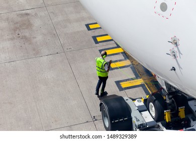 Manchester Airport, UK, August 2019 / Aircraft Dispatcher, Standing Next To An Aircraft Readying For Departure. Man Is Wearing A British Airways High Visibility Vest And Ear Defenders.