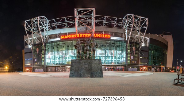 Panorama of the stadium Old Trafford and the statue "United Trinity" in the night. Wallpaper.