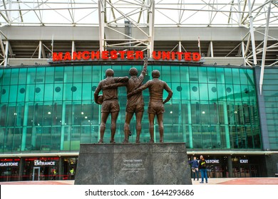 Manchester, England, UK - March 22, 2019 - Front view of Old Trafford with The United Trinity, a statue of Manchester United's "holy trinity" of Best, Law and Charlton