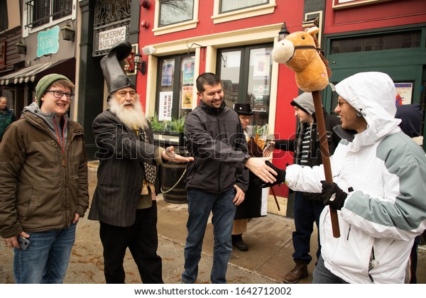 MANCHESTER, NEW HAMPSHIRE, USA - FEBRUARY 11,\
2020: A Libertarian 2020 presidential candidate known as Vermin\
Supreme, second from left, is seen in downtown Manchester, New\
Hampshire.