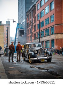 Manchester, UK - 07 04 2019: Two male actors dressed up in 1950s style clothing standing next to an old classical car. Movie set in Northern Quarter captured with 