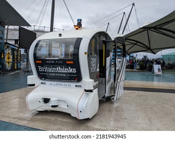 Manchester UK, July 24, 2022. Aurrigo Self Driving Auto-pod Trial At Etihad Campus. Driverless White Car In Rain With Text Centre For Connected And Autonomous Vehicles. Sensor Shielded From Rain.