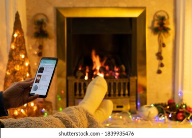 Manchester, UK. October 24, 2020. Cosy Christmas Scene In Front Of Open Fire. Shopping On Mobile Phone For Mulled Wine Or Spices. Shallow Depth Of Field. Illustrative Editorial. 