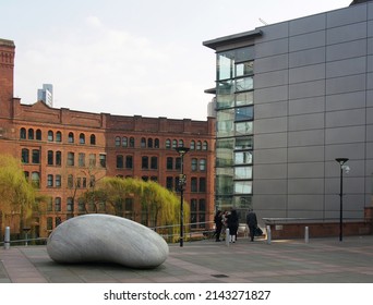 Manchester, United Kingdom - 24 March 2022: People Outside The Bridgewater Hall Concert Venue In Manchester City Centre With The Ishinki Touchstone Sculpture Outside The Building