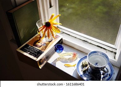 MANCHESTER, VT, UNITED STATES - Sep 12, 2017: Cannabis pipe by summer windowsill with sunflower, tea cup, a classic novel "Count of Monte Cristo" and sunlight streaming through.