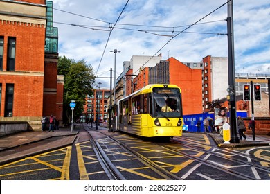 MANCHESTER,ENGLAND- OCTOBER 8,2014: A tram on the Metrolink light rail system passes the law courts on its way to Piccadilly Station.