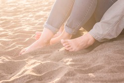 Feet of a young woman touching water containing feet, beach, and sand