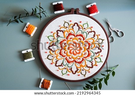 Mandala pattern design embroidery, colorful mandala design, hand made embroidery design, embroidery floss, needle craft, flat desk, green background,  top view with floss, small business concept.