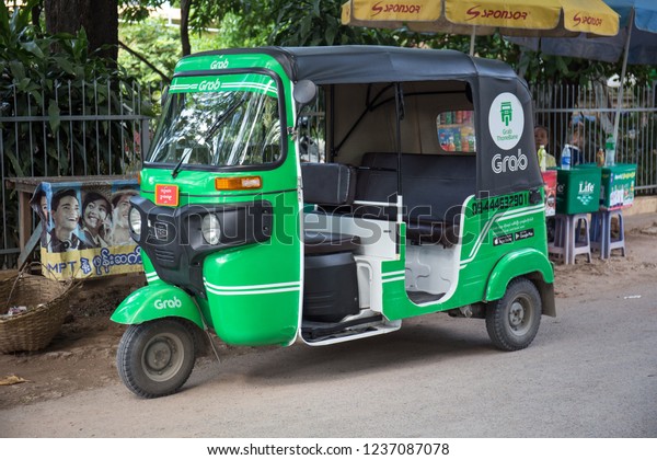 MANDALAY, MYANMAR -\
October 18, 2018. Grab branded three wheeled motor rickshaw is\
parking on the road\
side.
