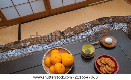 Mandarin oranges, green tea, sweet buns and rice crackers on the table.A view of the Japanese style room.Image of Japan.