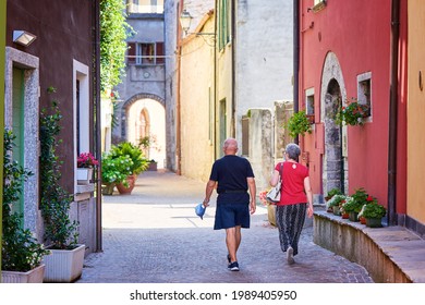 Mandello Del Lario, Italy - July 26, 2020. Senior Couple Traveling Together, Walking In Italian Village In Summer. Active Elderly And Travel Lifestyle Concept With Retired Mature People