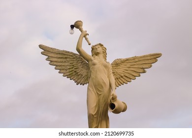 Mandiri Land, Jember, Indonesia - January 23, 2022: The image of an angel statue holding a glass and a lamp looks aesthetic when photographed during the day with the camera positioned from the front