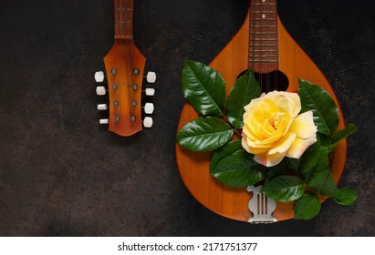 Mandolin - a stringed plucked musical instrument and a beautiful yellow tea rose flower