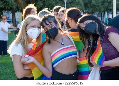 Manduria, Italy - JULY, 13, 2022 Group Of Teen Girls With Black Face Mask Wearing A Rainbow Flag During The LGBT Gay Pride March. LGBTQ Pride Day Celebrations In The Street