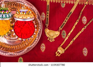 
Mangalsutra or Golden Necklace to wear by a married hindu women, arranged with traditional saree with haldi, kumkum and grain rice on plate. Indian Traditional Jewellery.