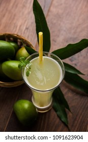 Mango juice OR Aam Panna or Panha in a transparent glass with whole green fruit, selective focus