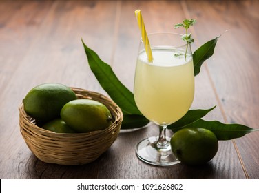 Mango juice OR Aam Panna or Panha in a transparent glass with whole green fruit, selective focus
