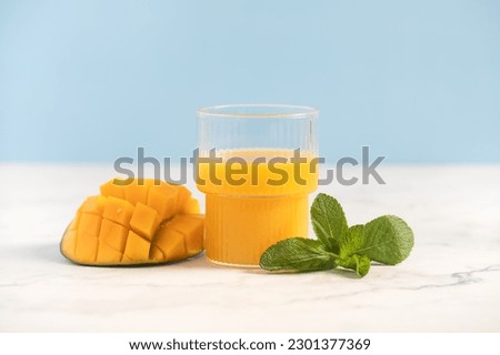 
Mango juice in a glass. tropical juice. Lemonade. Mint leaves. Blue background. Summer drink.
