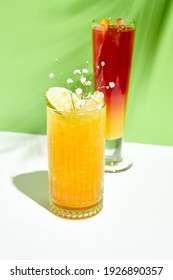 Mango Limonade Getränk auf grünem Hintergrund. Weißer Tisch mit Sonnenlicht und Schatten aus Palmenblättern. Konzept "Sommer", "Tropisch" und "saftig"