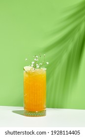 Mango Limonade Getränk auf grünem Hintergrund. Weißer Tisch mit Sonnenlicht und Schatten aus Palmenblättern. Konzept "Sommer", "Tropisch" und "saftig"