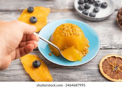 Mango and passion fruit jelly with blueberry with hand on gray wooden background. side view, close up, selective focus. - Powered by Shutterstock