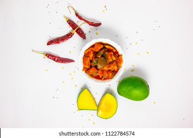 Mango pickle top view with chillies and raw mango isolated on white background