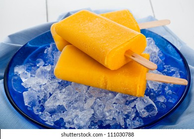 Mango popsicle on blue plate with ice