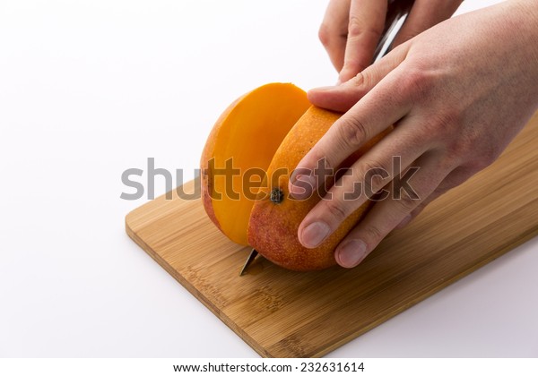 A mango positioned
firmly on a cutting board and sliced along the flat side of the
core of the fruit. The resulting slice reveals the bright orange
pulp of the ripe mango.