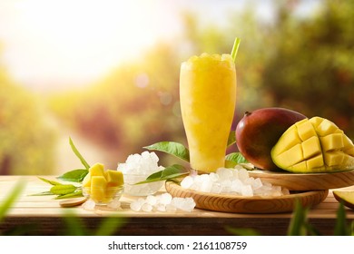 Mango Slush With Fruit And Crushed Ice Around It On A Wooden Table Outside With Crop In Background. Front View. Horizontal Composition.