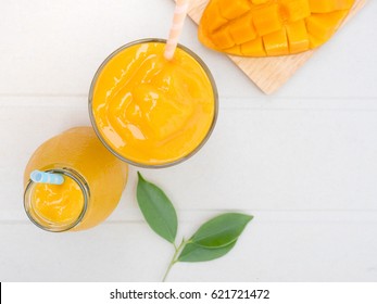 Mango Smoothie In Glass And Bottle With Diced Mango Top View.