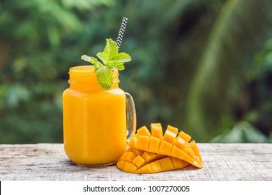 Mango Smoothie In A Glass Mason Jar And Mango On A Green Background. Mango Shake. Tropical Fruit Concept.