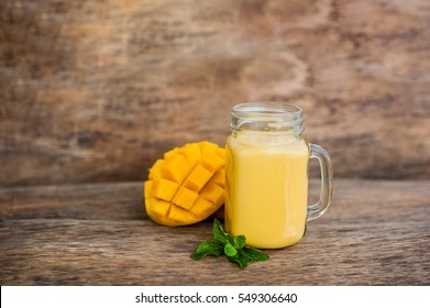 Mango smoothie in a glass Mason jar and mango on the old wooden background. Mango shake. Tropical fruit concept.