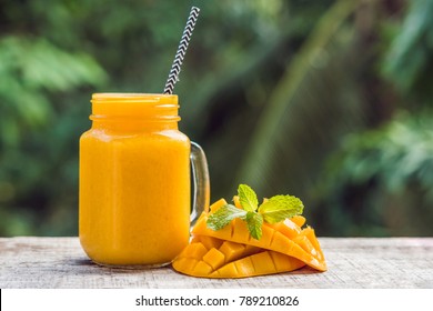 Mango Smoothie In A Glass Mason Jar And Mango On A Green Background. Mango Shake. Tropical Fruit Concept.