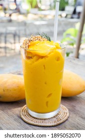 Mango smoothie with Toasted coconut in a glass Mason jar and mango  on the old wooden background. Mango shake. Tropical fruit concept.