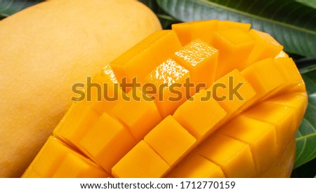 Mango, tropical fruit, in a bamboo wooden sieve basket on green leaf background, top view, full frame, beautiful, ripe harvest design concept.
