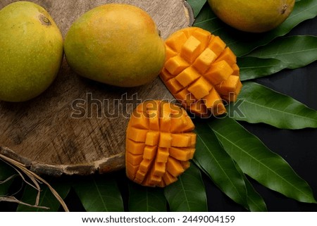 Mango tropical fruit with slice and half cut on green leaf background