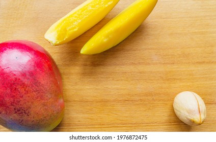 Mango, Mango Wedge And Avocado Seeds On Kitchen Board