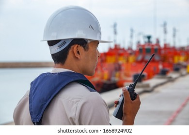 Mangystau, Kazakhstan - May 19 2012: Bautino bay. Loading terminal on Caspian sea. Engineer in hardhat and life vest with radio set. Orange oil tanker ships. 