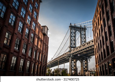 Manhattan bridge seen from a narrow alley enclosed by two brick buildings on a sunny day in summer
