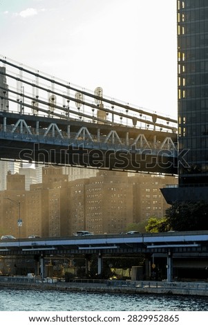 Manhattan Bridge structure and skyscraper in New York. Steel suspension bridge over elevated highway with brick buildings and glass tower.