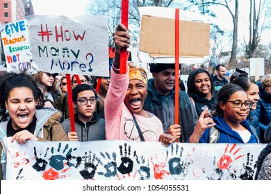 Manhattan, New York City / USA - March 24th 2018: March For Our Lives. Portrait Of African American Teen Protesting Holding Sign In A Large Group Of Students Screaming, Holding Sign How Many More?