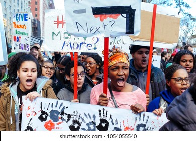 Manhattan, New York City / USA - March 24th 2018: March for our lives. Portrait of African American teen protesting holding sign within a large group of young students screaming