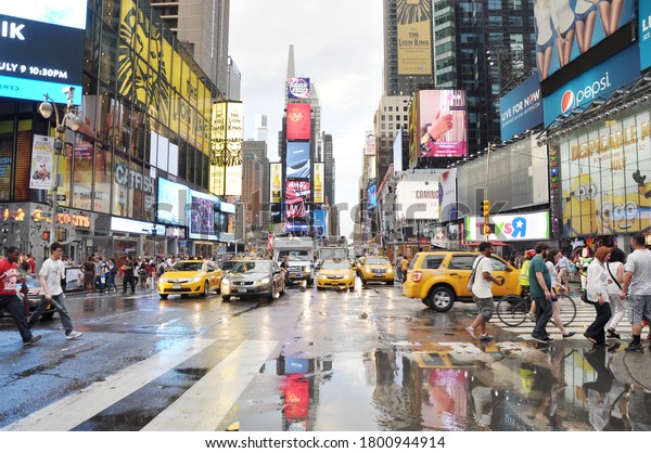 MANHATTAN,\
NEW YORK, USA - JULY3, 2013: Large puddles of rain water on wet\
Broadway Avenue at 44th Street with taxis, cars and pedestrians\
passing by in the big apple theater district\
