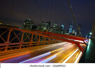 Manhattan Skyline And Cars Crossing Brooklyn Bridge At Night, New York City