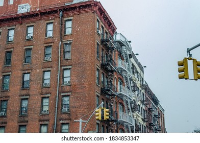 Manhattan Soho Building With Fire Escape Ladders On A Snowy Day Of Winter. Classic Yellow Traffic Lights On The Street