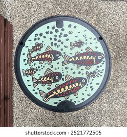 A manhole cover with a colorful fish pattern in Gujo-Hachiman, Gifu Prefecture, Japan.