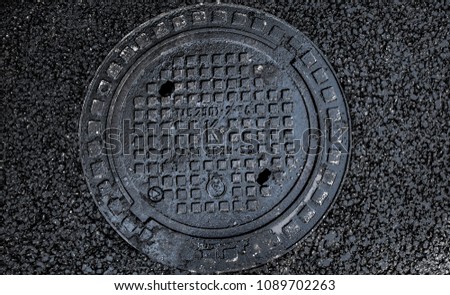 manhole cover in the road of asphalt