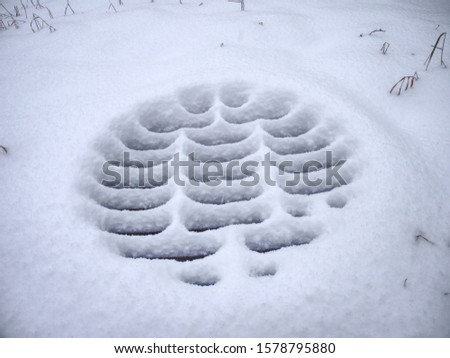 Manhole covers after snowfall covered by snow. Snow Covered Sewer enter. Pattern of snow deposits on a metal grid