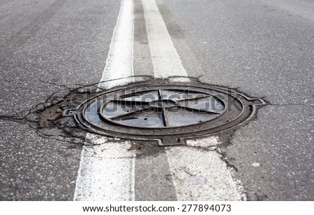 Manhole on the road within the double solid white center-lines of the road marking