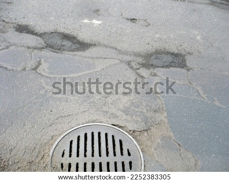 A manhole and potholes in the street